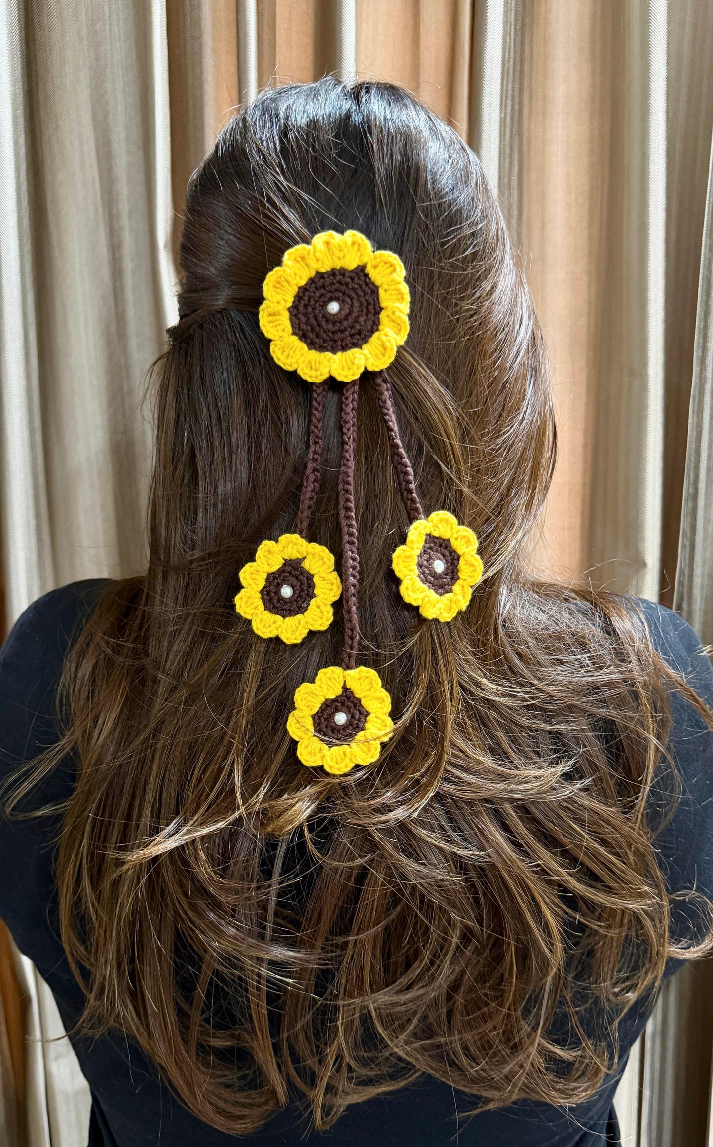 Sunflower Tassel Hair Charm with one large yellow crochet sunflower and three cascading mini blooms styled on long hair.