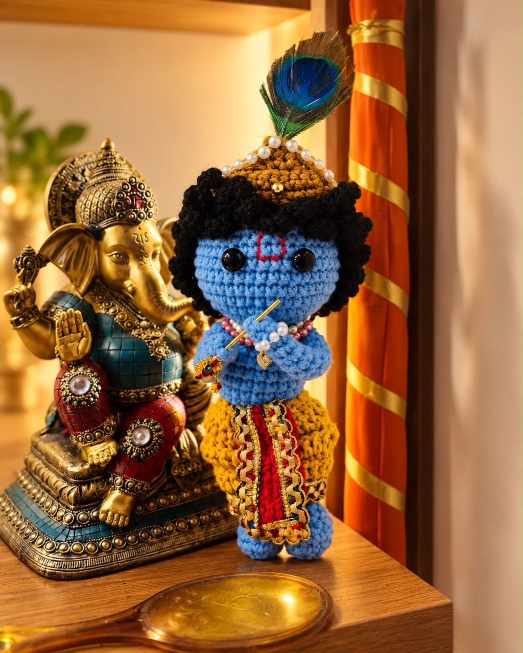 Handmade Crochet Krishna Ji displayed beside a decorative Ganesha statue on a wooden shelf