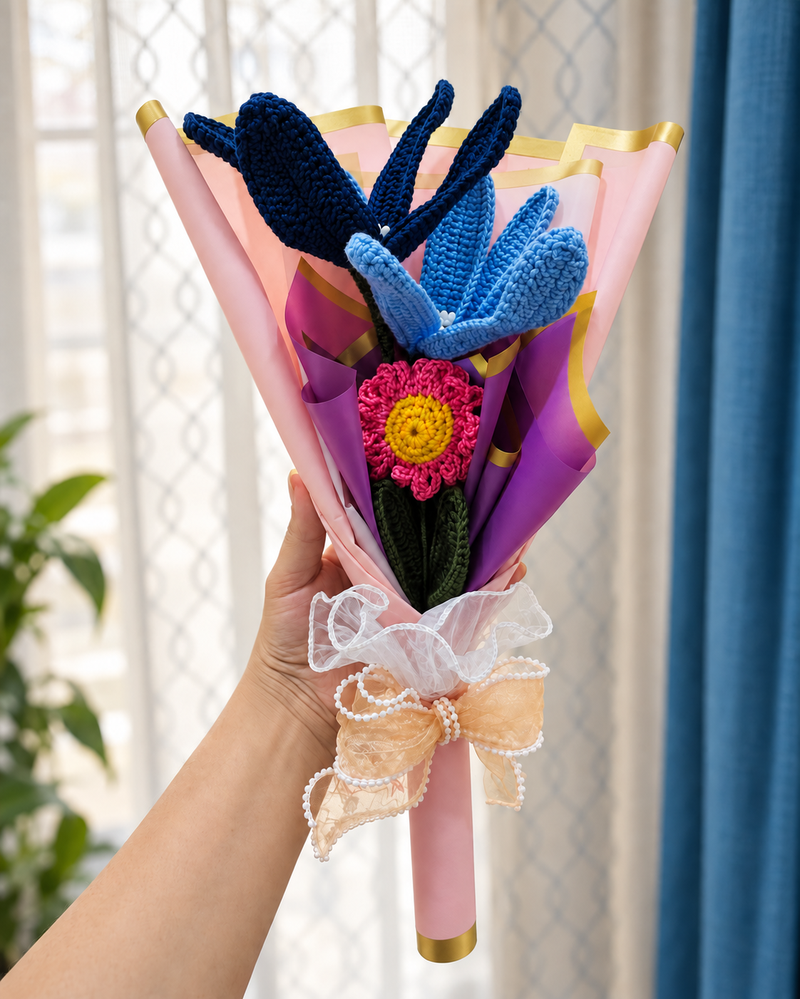 Enchanted Harmony Bouquet held by hand beside a window, showing its size and ribbon bow.