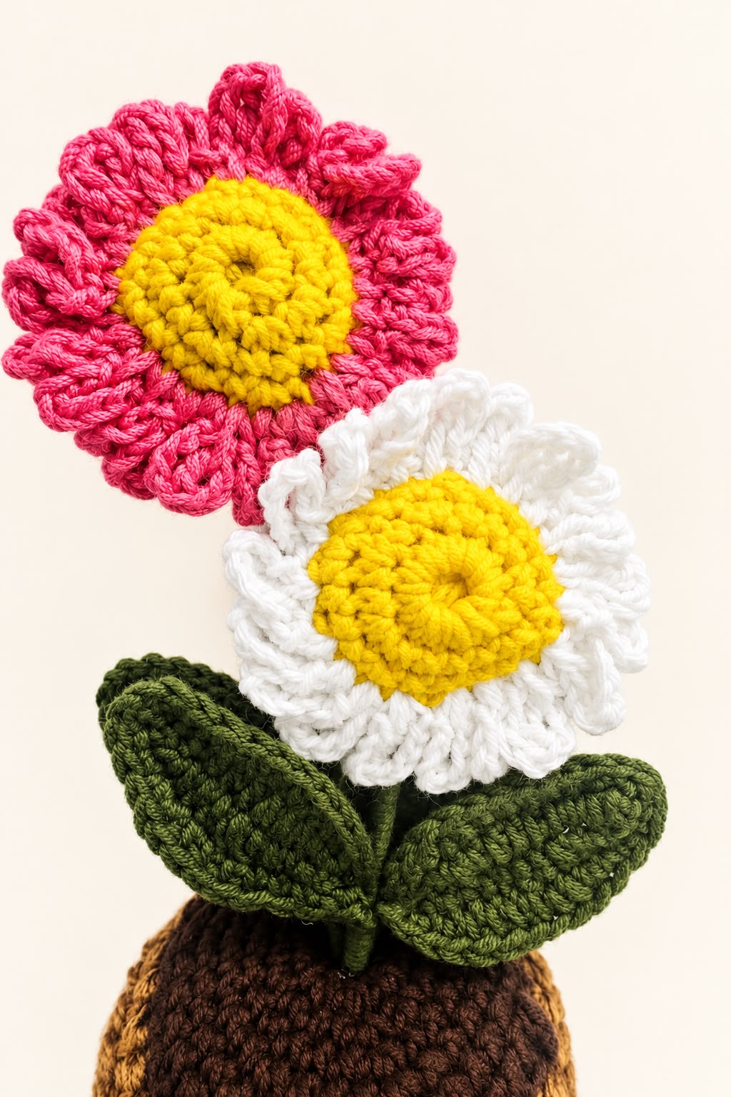 Close-up of Blush Daisy Duo Pot showing pink and white petals, yellow centres and green crochet leaves