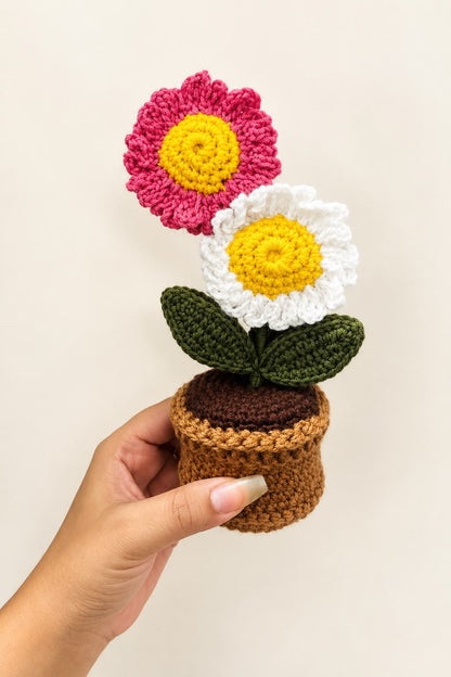 Blush Daisy Duo Pot held in a hand, showing the pink and white crochet daisies and pot