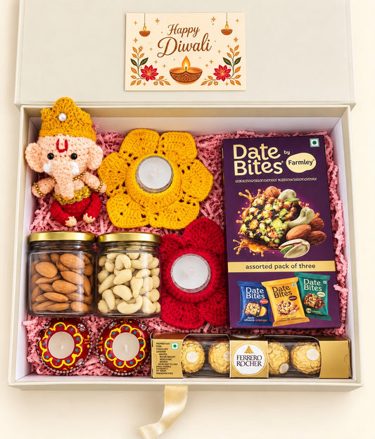 Overhead view of Divine Blessings Diwali gift hamper arranged in an ivory box with pink paper filling
