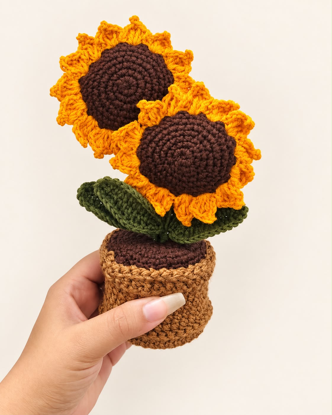 Golden Sunflower Duo Pot held in a hand, showing the two crochet sunflowers and pot