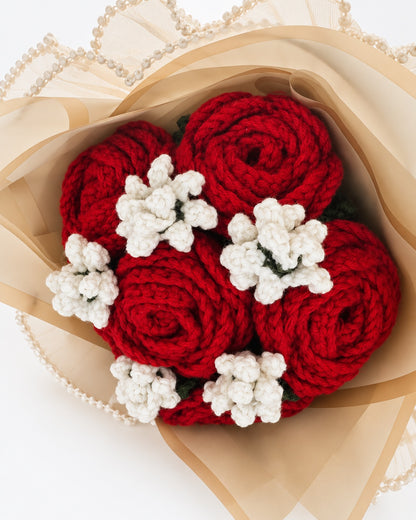 Close-up of handmade crimson crochet roses and white crochet fillers