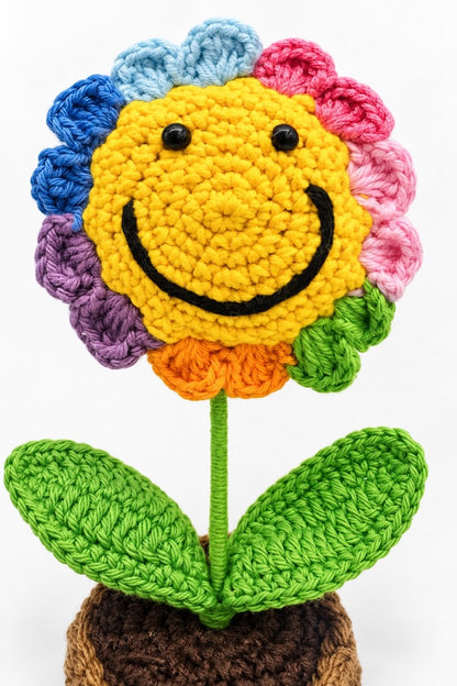 Close-up of the smiling flower face, rainbow crochet petals and green leaf stitching
