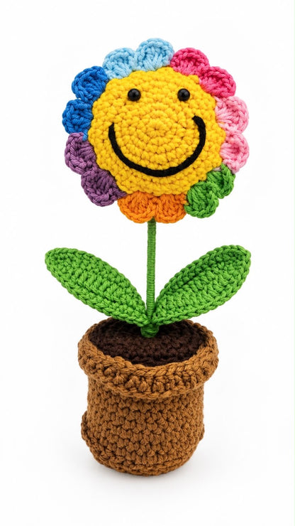 Rainbow Joy Bloom Pot with a smiling yellow crochet flower, multicoloured petals and green leaves in a brown crochet pot