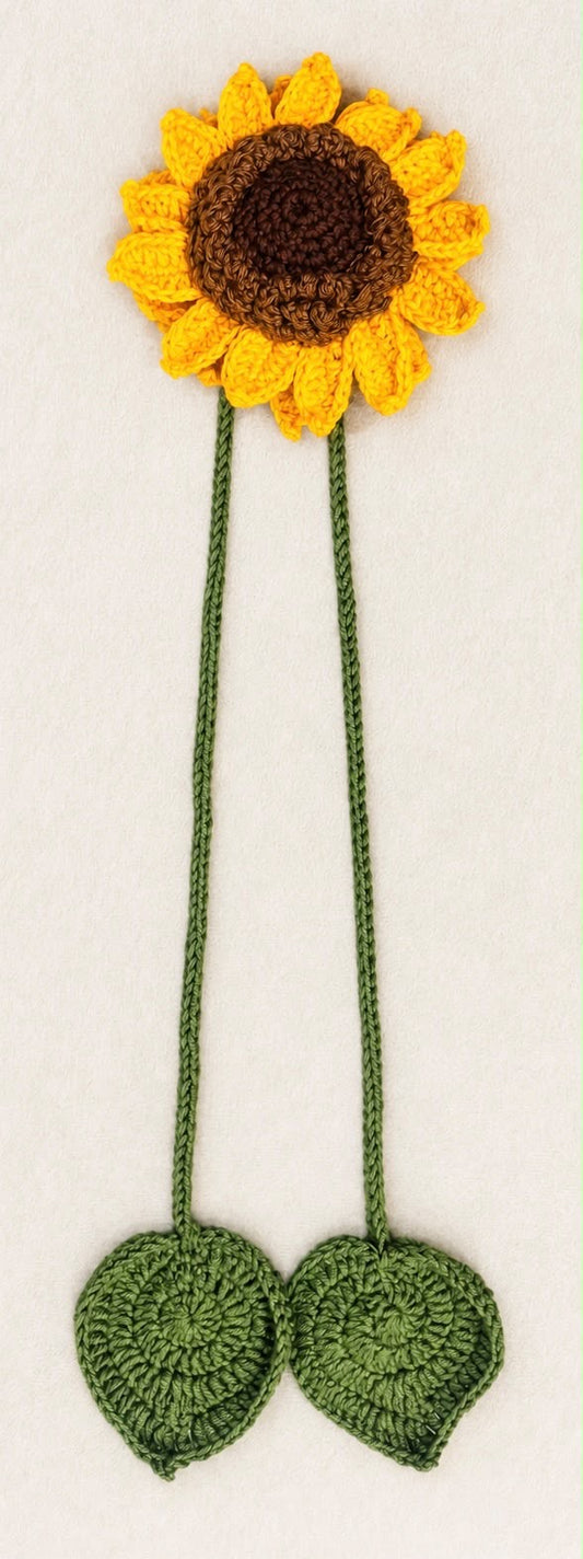 Full-length handmade sunflower curtain tieback laid flat, showing yellow petals, a brown centre and two green cords ending in crochet leaves.