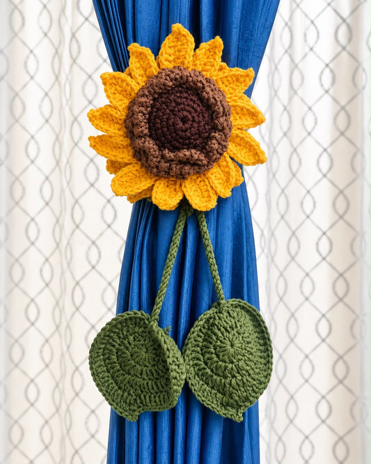 Handmade yellow crochet sunflower curtain tieback with brown center and green leaves on a blue curtain